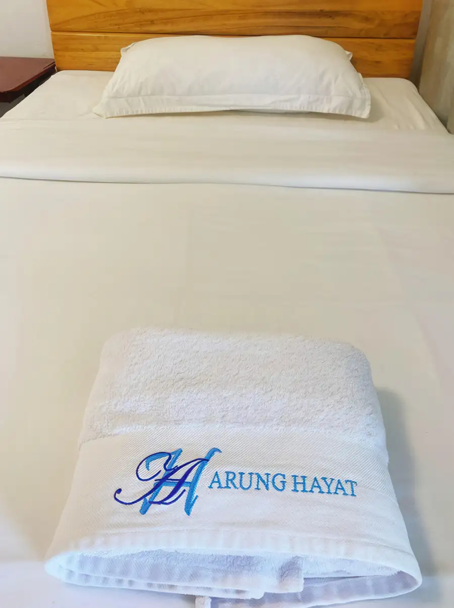 Branded towel fold on the bed in the Deluxe Double Room at Amina Holidays