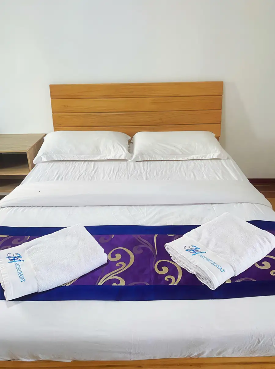 Deluxe double bed with white linen at Amina Holidays overwater resort
