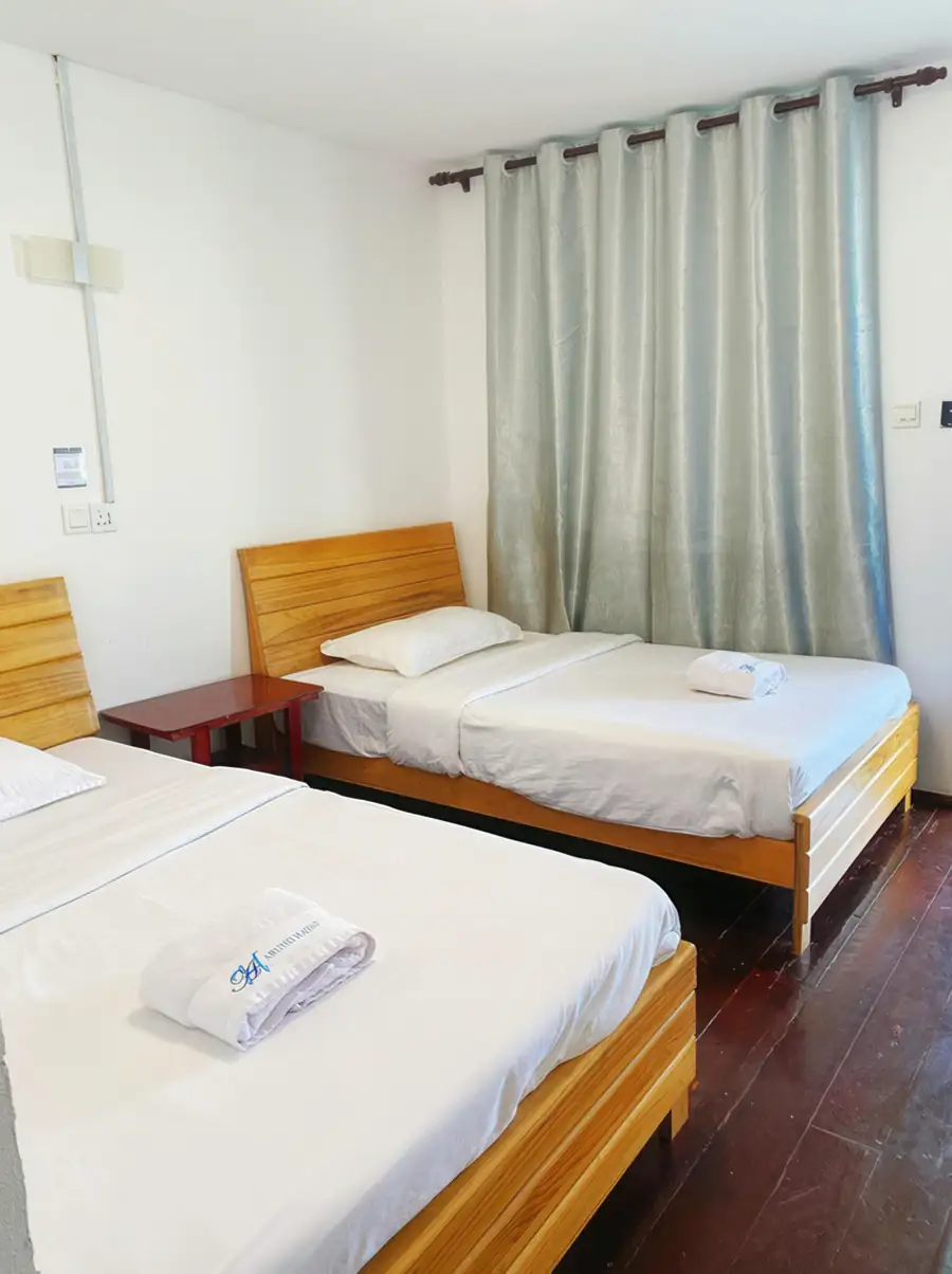 Two comfortable twin beds with teak floors in the Deluxe Twin Room at Amina Holidays